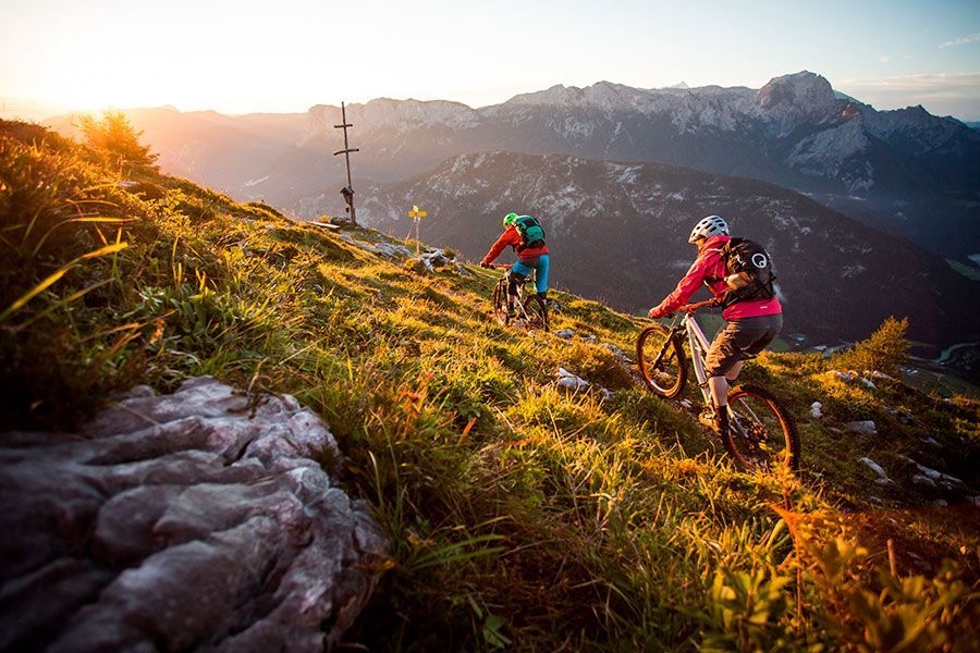 Zwei Mountainbiker fahren dem Sonnenaufgang entgegen